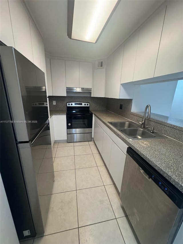 kitchen with light tile patterned floors, appliances with stainless steel finishes, sink, and white cabinetry