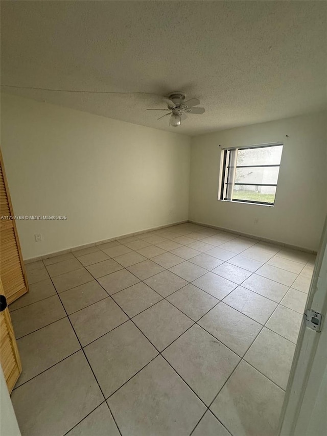 unfurnished room featuring ceiling fan, light tile patterned flooring, and a textured ceiling