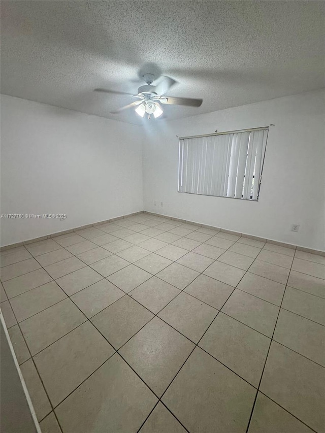 tiled empty room with ceiling fan and a textured ceiling