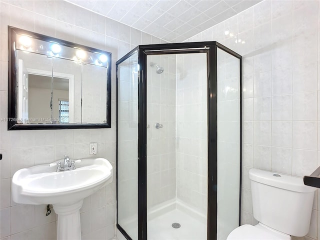 bathroom featuring a shower with shower door, tile walls, and toilet