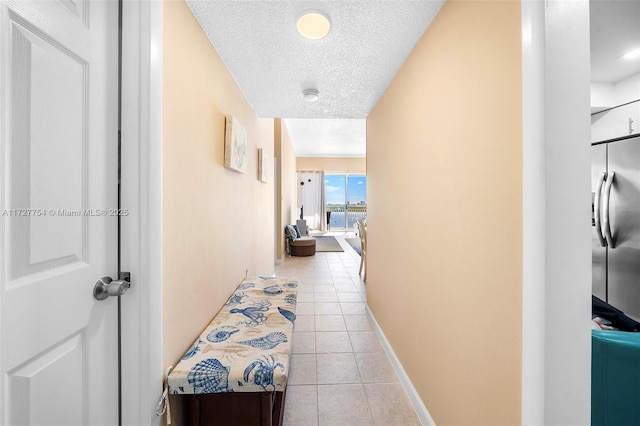 hallway with a textured ceiling and light tile patterned flooring