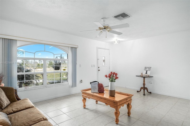 living room with ceiling fan and a textured ceiling