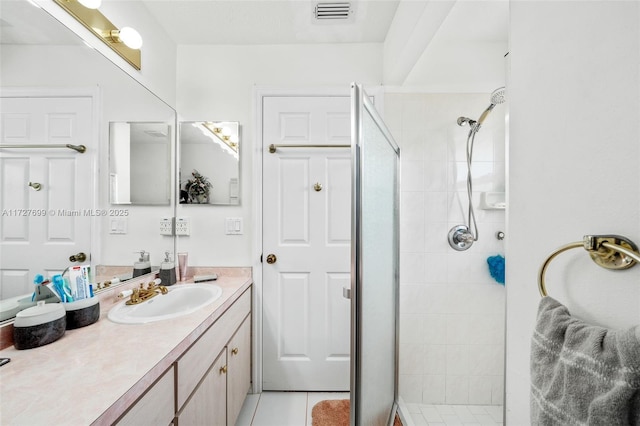 bathroom with vanity, a tile shower, and tile patterned flooring