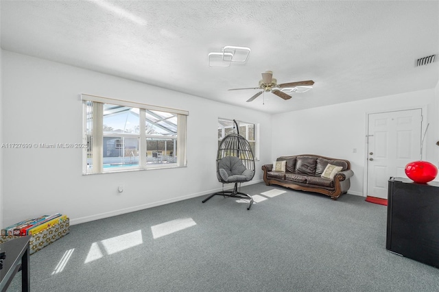 sitting room featuring ceiling fan, carpet, and a textured ceiling