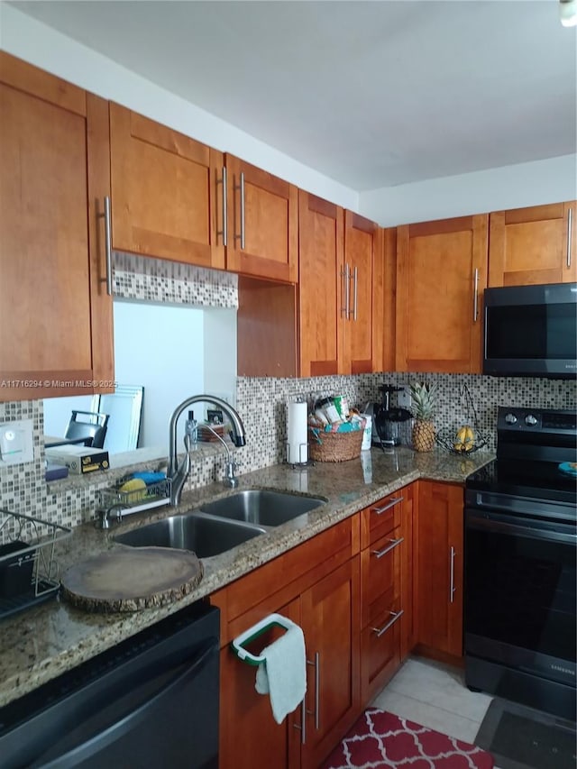 kitchen with light stone countertops, sink, tasteful backsplash, and black appliances