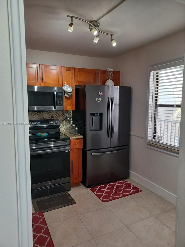 kitchen featuring tasteful backsplash, light stone countertops, stainless steel appliances, and light tile patterned flooring