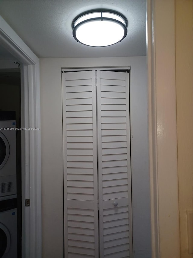 room details with stacked washing maching and dryer and a textured ceiling