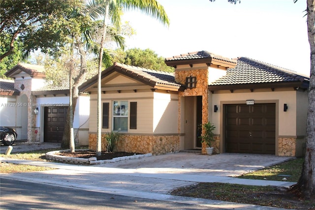 mediterranean / spanish-style house featuring an attached garage, stone siding, driveway, and a tile roof