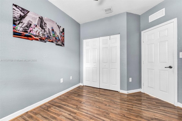 unfurnished bedroom featuring baseboards, a closet, visible vents, and dark wood-type flooring