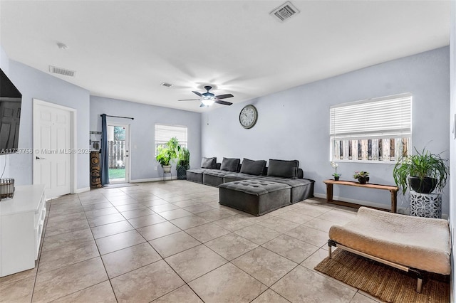 living room featuring a ceiling fan, visible vents, baseboards, and light tile patterned floors