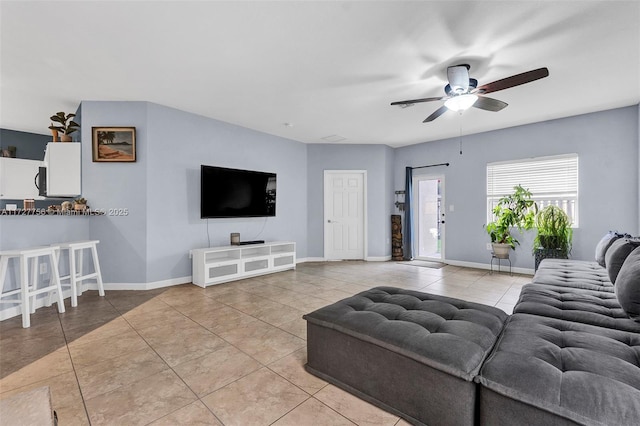 living area featuring ceiling fan, light tile patterned flooring, and baseboards