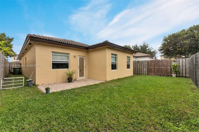 rear view of house with a fenced backyard, a lawn, and stucco siding