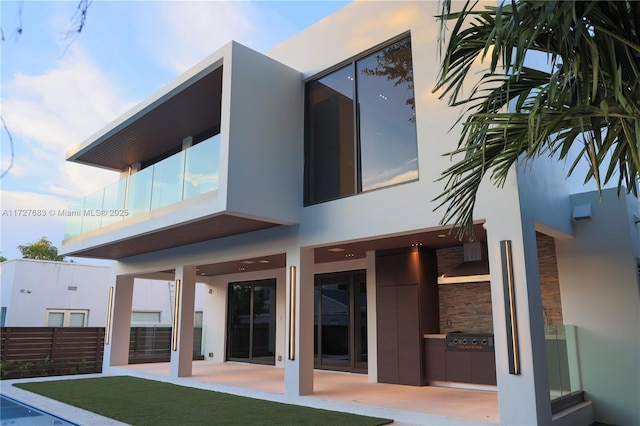 rear view of property with a lawn, an outdoor kitchen, and a patio