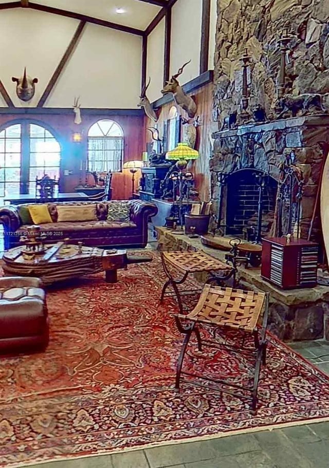 living room featuring a stone fireplace and a towering ceiling