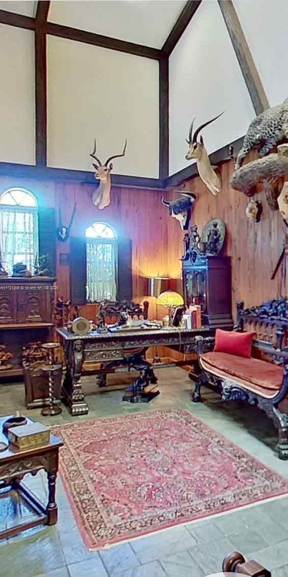 miscellaneous room with a towering ceiling and wood walls