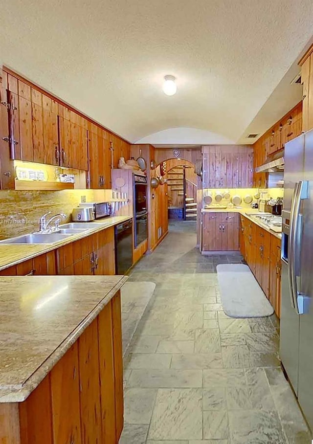 kitchen with sink, vaulted ceiling, black appliances, and a textured ceiling