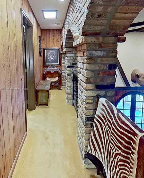 corridor featuring light carpet and wooden walls