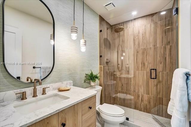 bathroom featuring toilet, vanity, and an enclosed shower