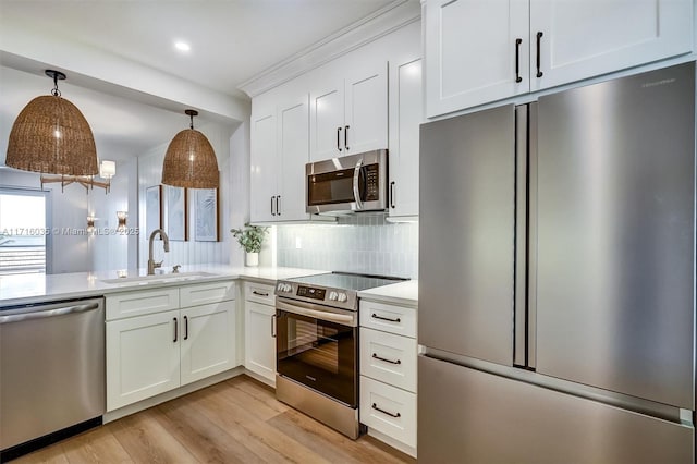 kitchen featuring white cabinetry, sink, hanging light fixtures, and appliances with stainless steel finishes