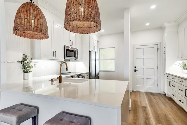 kitchen with white cabinetry, stainless steel appliances, kitchen peninsula, and a breakfast bar