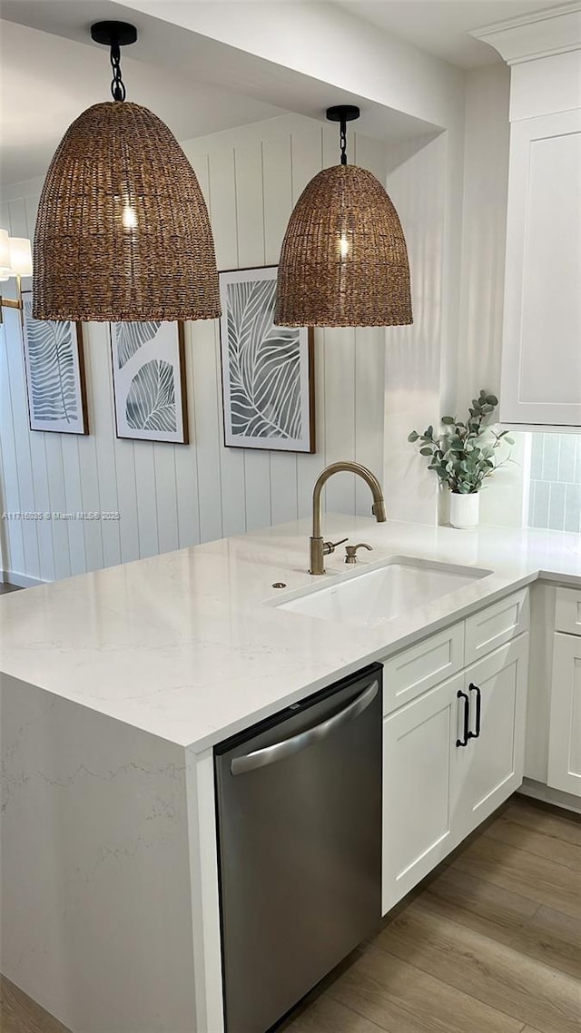 kitchen with decorative light fixtures, dishwasher, sink, and white cabinetry