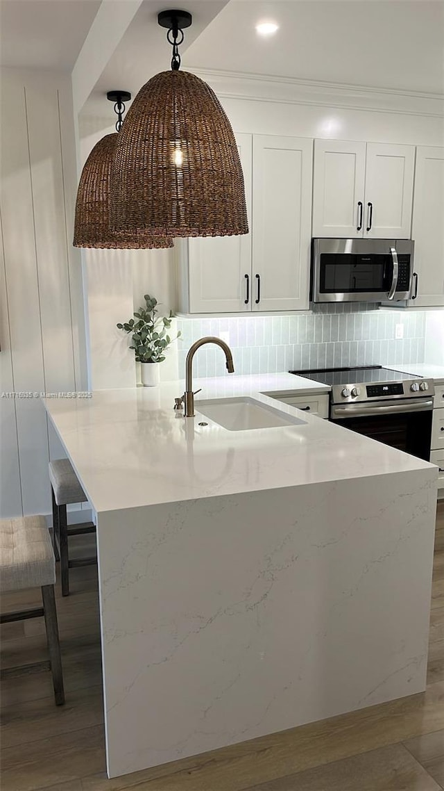 kitchen featuring tasteful backsplash, sink, white cabinetry, hanging light fixtures, and stainless steel appliances