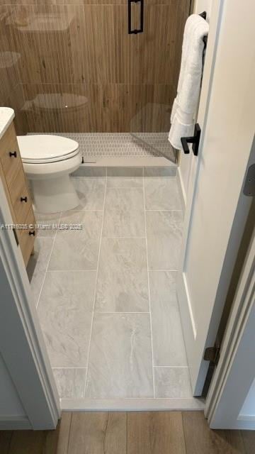 bathroom featuring toilet, a shower, tile patterned flooring, and vanity