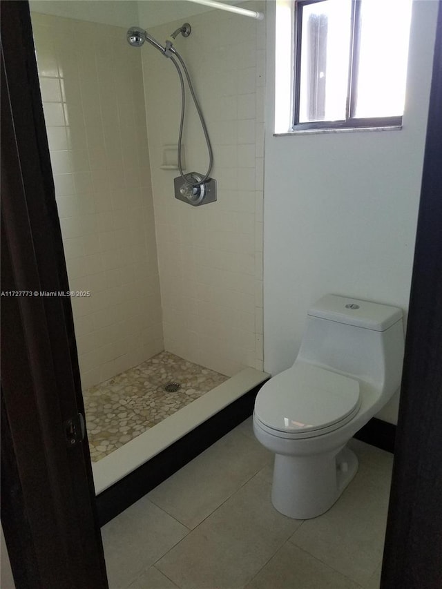 bathroom with toilet, tile patterned flooring, and a stall shower