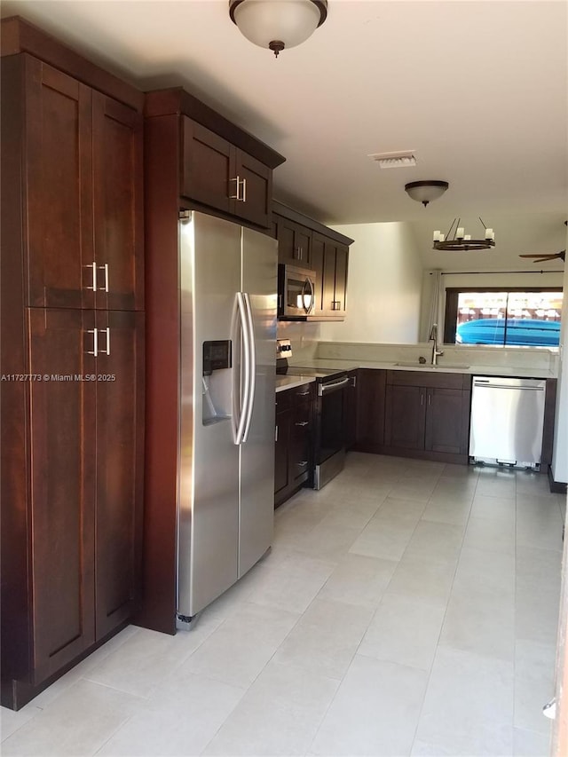 kitchen with light countertops, dark brown cabinets, visible vents, a sink, and appliances with stainless steel finishes