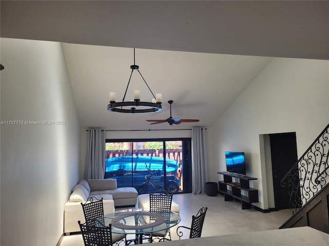 living area with light tile patterned floors, stairway, high vaulted ceiling, and ceiling fan with notable chandelier