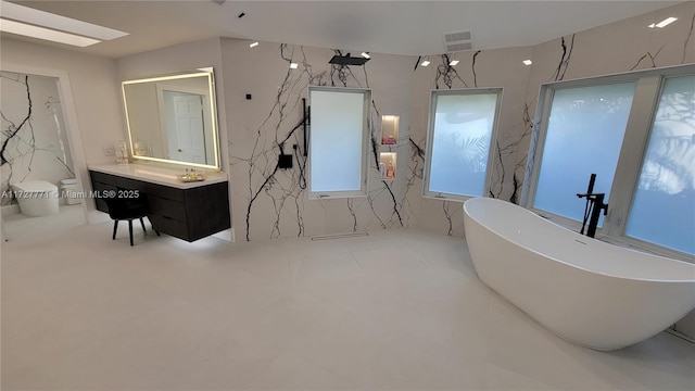 bathroom with vanity, a bath, and a skylight