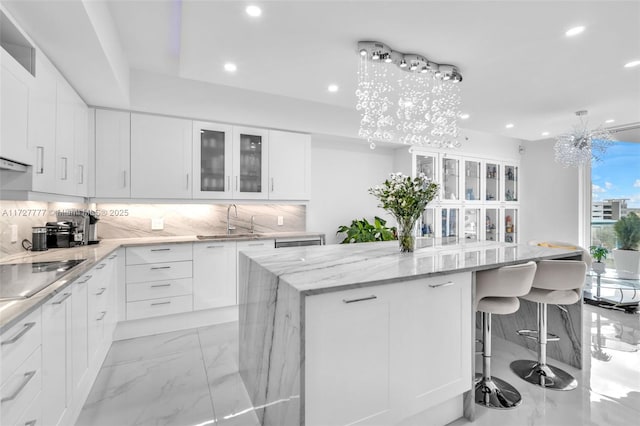 kitchen featuring sink, white cabinetry, black electric cooktop, and a chandelier