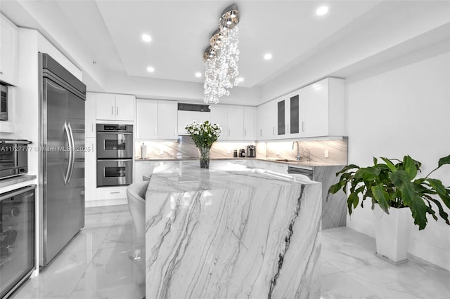 kitchen with sink, appliances with stainless steel finishes, white cabinets, beverage cooler, and light stone counters