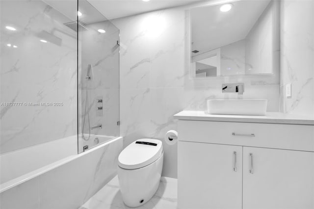 full bathroom featuring toilet, tile walls, tiled shower / bath, and vanity