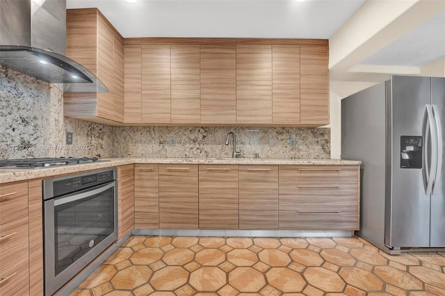 kitchen featuring wall chimney exhaust hood, tasteful backsplash, stainless steel appliances, and light stone counters