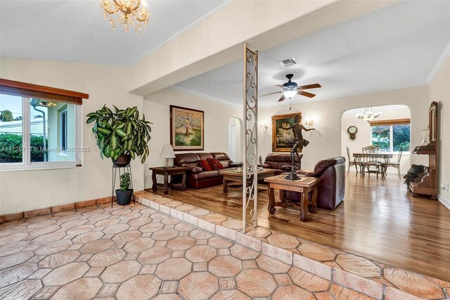 living room featuring hardwood / wood-style flooring, ceiling fan with notable chandelier, and ornamental molding