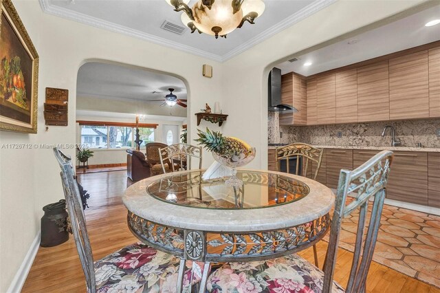 dining area with crown molding, sink, ceiling fan, and light hardwood / wood-style flooring