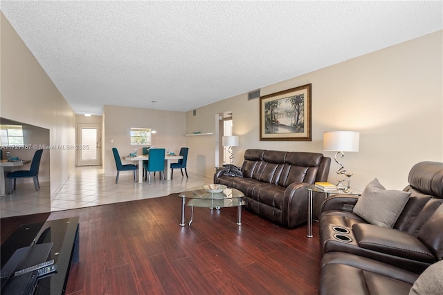 living room featuring a textured ceiling, visible vents, and wood finished floors