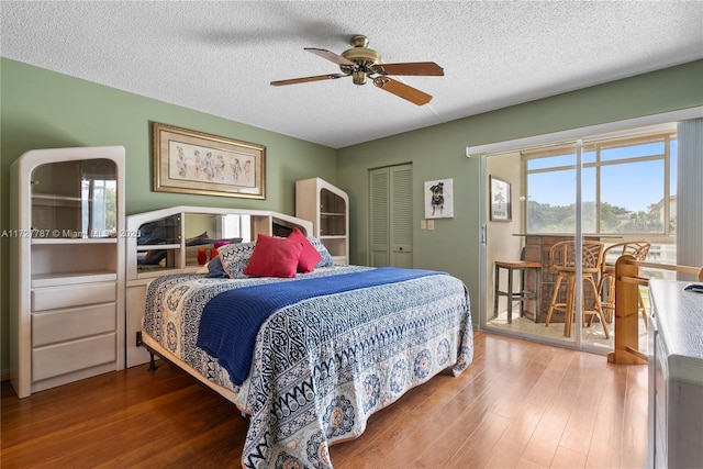 bedroom with ceiling fan, a textured ceiling, wood finished floors, and access to exterior