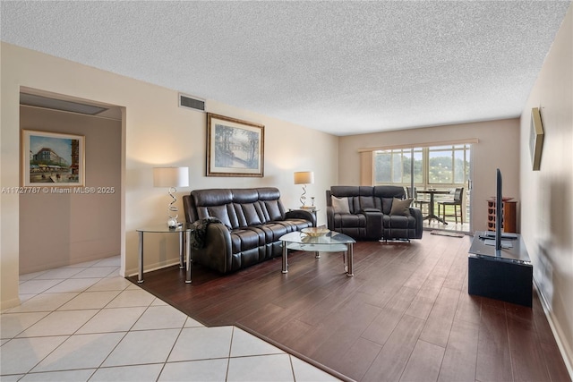 living room featuring light wood-style floors, visible vents, and a textured ceiling