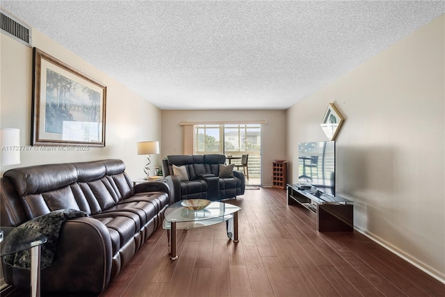 living area with a textured ceiling, dark wood-style flooring, visible vents, and baseboards