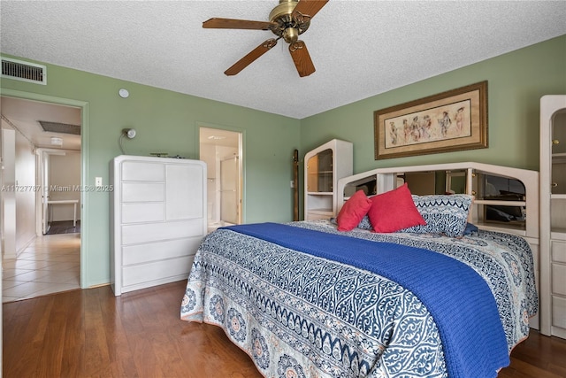 bedroom with a textured ceiling, visible vents, arched walkways, and wood finished floors