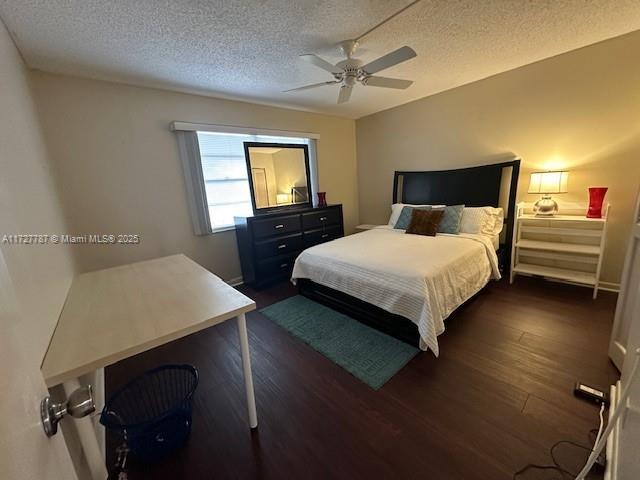 bedroom featuring ceiling fan, dark wood-type flooring, and a textured ceiling