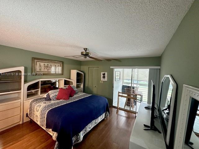 bedroom featuring dark wood-type flooring, a textured ceiling, and ceiling fan