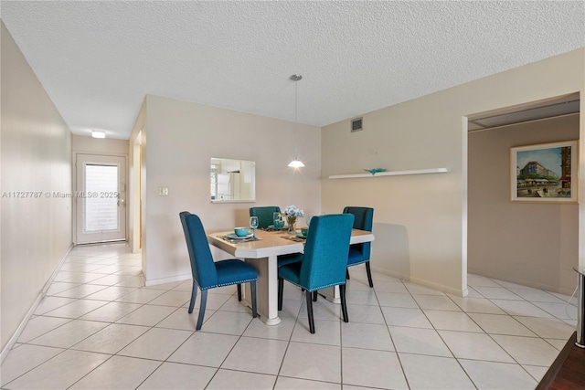 dining space featuring light tile patterned floors, baseboards, and a textured ceiling