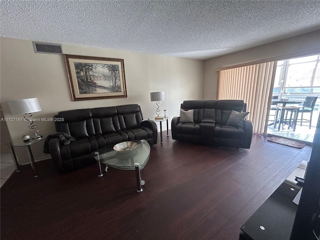 living area featuring a textured ceiling, dark wood-style flooring, and visible vents