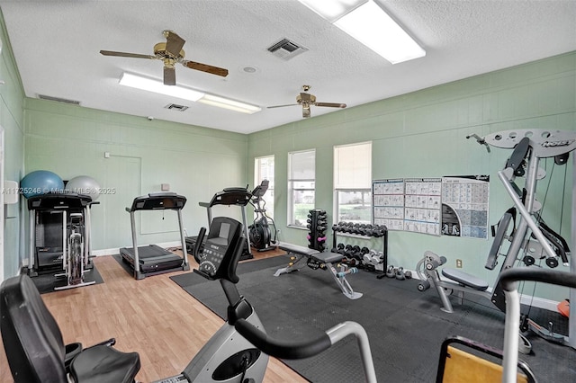 workout area featuring ceiling fan, wood-type flooring, and a textured ceiling