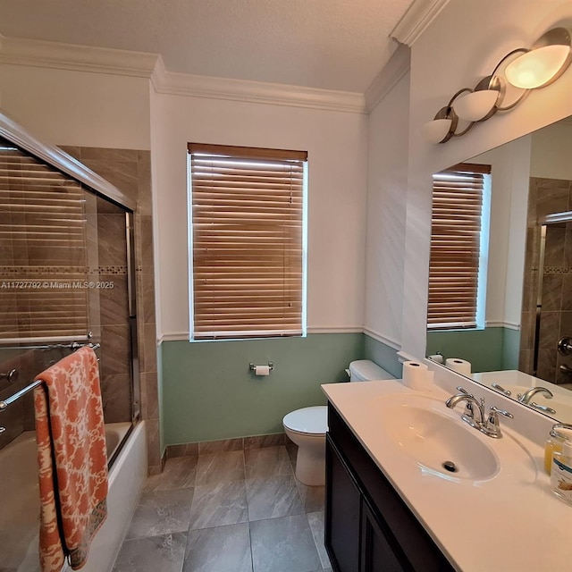 bathroom featuring crown molding, baseboards, bath / shower combo with glass door, toilet, and vanity