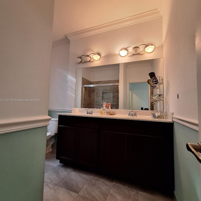 full bathroom with a shower stall, toilet, ornamental molding, and double vanity