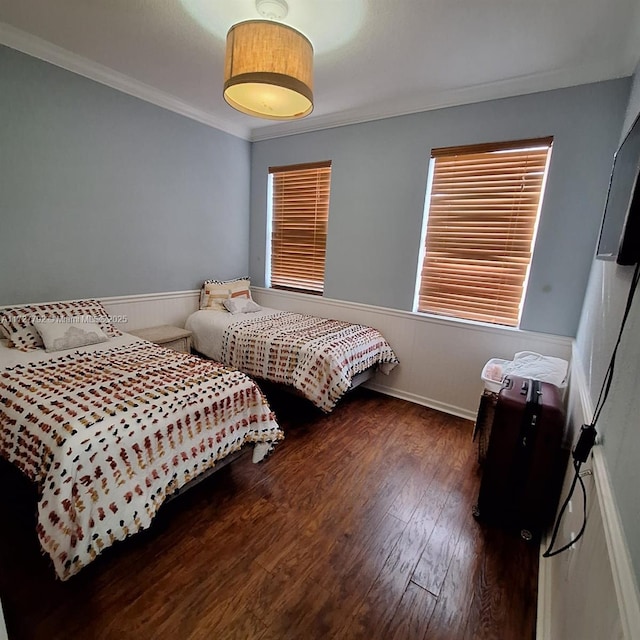 bedroom featuring wood finished floors, ornamental molding, and wainscoting